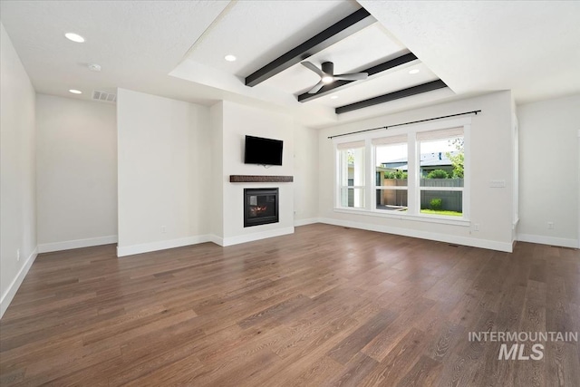 unfurnished living room featuring a glass covered fireplace, wood finished floors, baseboards, recessed lighting, and beam ceiling