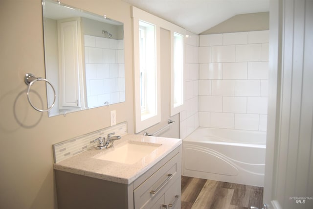 bathroom featuring tasteful backsplash, wood finished floors, shower / washtub combination, vanity, and lofted ceiling