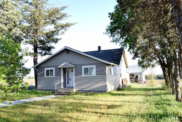 bungalow-style house with entry steps, a chimney, and a front yard