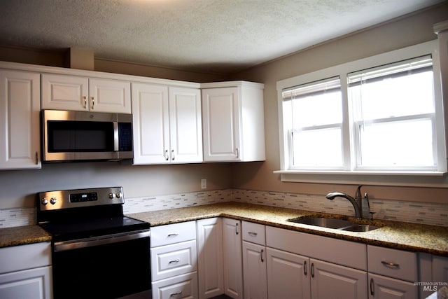 kitchen featuring backsplash, a textured ceiling, appliances with stainless steel finishes, a sink, and white cabinets