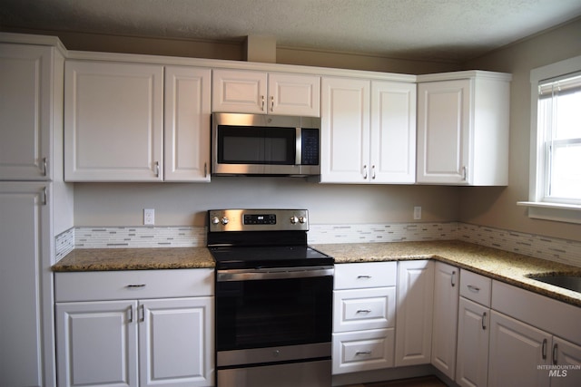kitchen featuring appliances with stainless steel finishes, light stone countertops, backsplash, and white cabinetry