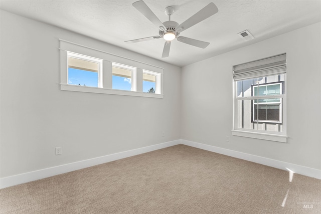 carpeted spare room featuring a ceiling fan, baseboards, visible vents, and a textured ceiling