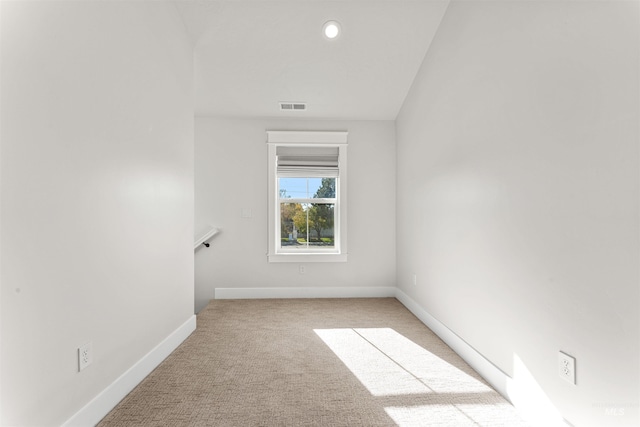 empty room with baseboards, visible vents, and light carpet