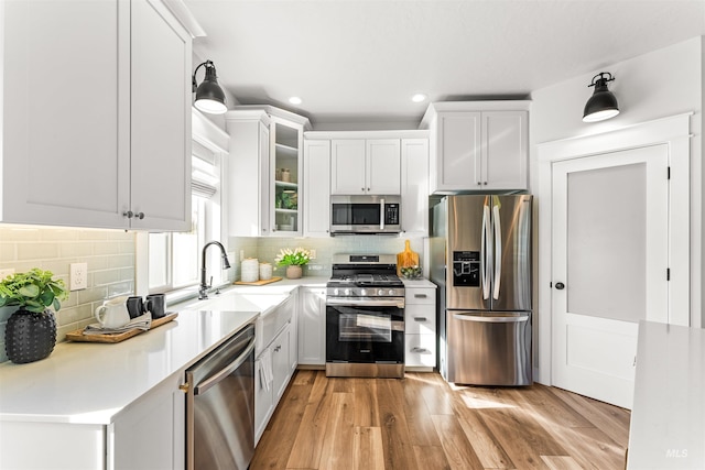 kitchen with white cabinets, glass insert cabinets, stainless steel appliances, and a sink