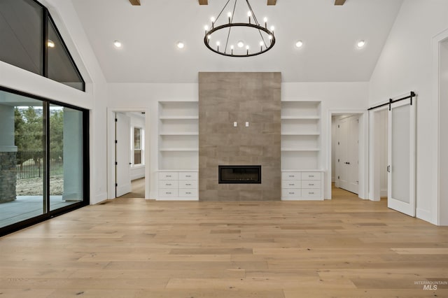 11444 N 17th Way, Boise, ID 83714 - unfurnished living room featuring built in features, a barn door, light wood-type flooring, baseboards, and high vaulted ceiling