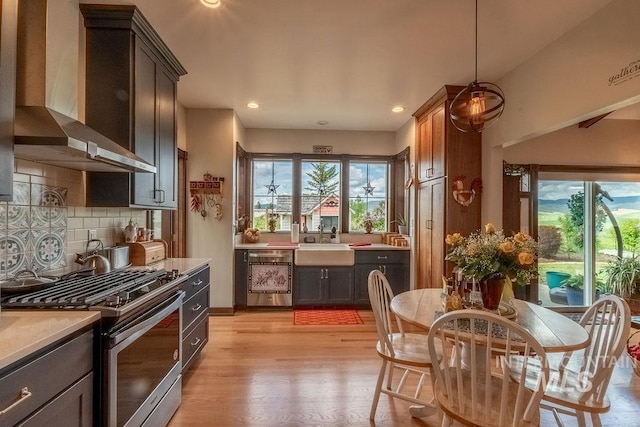 2350 Trail Rd, Moscow, ID 83843 - kitchen with stainless steel gas range oven, wall chimney range hood, a sink, light wood-style flooring, and light countertops