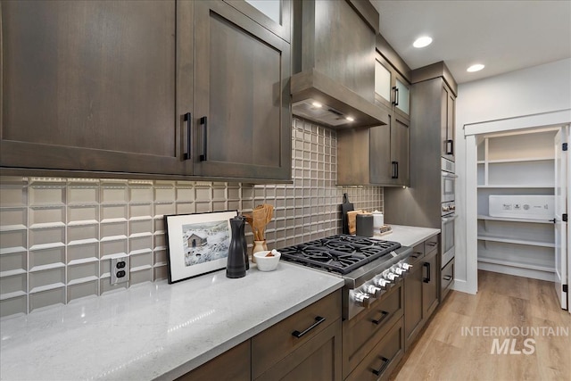 1071 E Star Pine Ln, Eagle, ID 83616 - kitchen featuring stainless steel gas cooktop, custom range hood, decorative backsplash, light wood-style floors, and dark brown cabinets