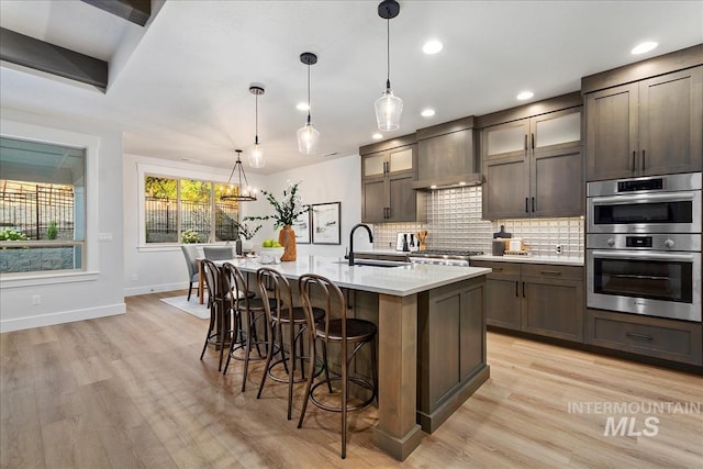 1071 E Star Pine Ln, Eagle, ID 83616 - kitchen featuring wall chimney range hood, decorative backsplash, a kitchen breakfast bar, recessed lighting, and baseboards