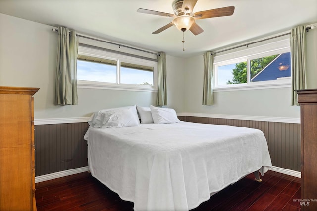 2074 11th Ave E, Twin Falls, ID 83301 - bedroom featuring dark wood-style flooring, a wainscoted wall, a ceiling fan, wooden walls, and baseboards