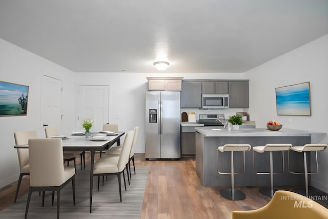 4044 W Ski Jump Ln, Meridian, ID 83642 - kitchen featuring light countertops, light wood-style flooring, a breakfast bar, baseboards, and appliances with stainless steel finishes