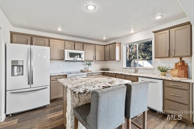 kitchen with a kitchen island, white appliances, dark hardwood / wood-style floors, and light stone countertops