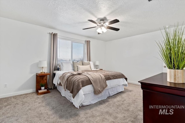 carpeted bedroom featuring ceiling fan and a textured ceiling