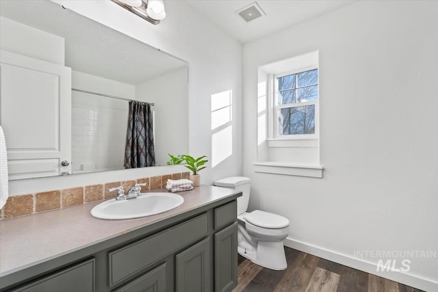 bathroom with wood-type flooring, curtained shower, vanity, and toilet