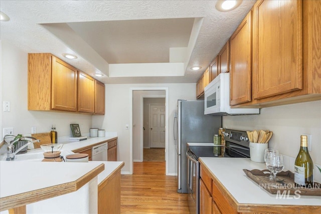 14325 W Comisky, Boise, ID 83713 - kitchen featuring white appliances, light countertops, light wood-style floors, a tray ceiling, and brown cabinets