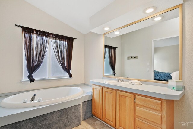 bathroom featuring tile patterned floors, vaulted ceiling, a bathtub, and vanity