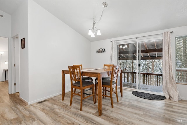 dining area featuring a chandelier, light wood-type flooring, and vaulted ceiling