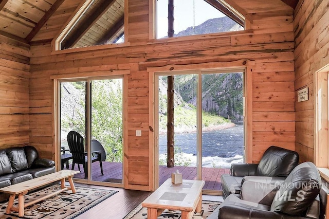 living room with a mountain view, wood-type flooring, wood walls, high vaulted ceiling, and wood ceiling