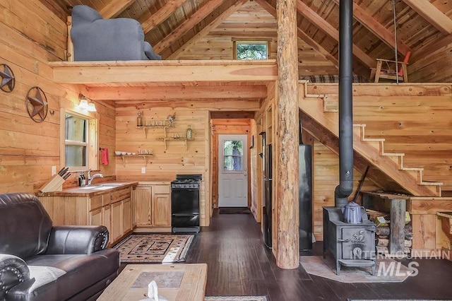 living room with beam ceiling, dark wood-type flooring, wooden walls, sink, and wooden ceiling