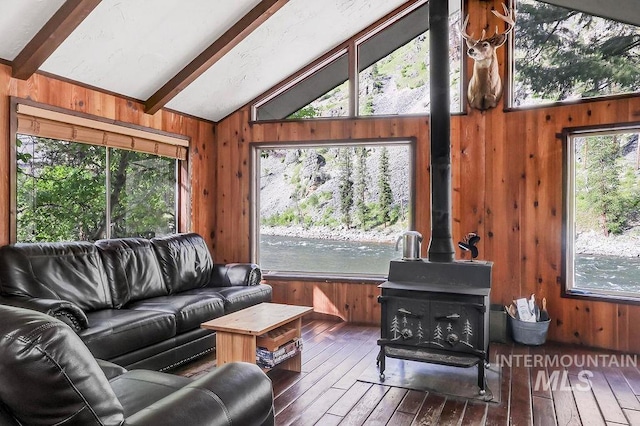 living room with wooden walls, lofted ceiling with beams, hardwood / wood-style flooring, and a wood stove