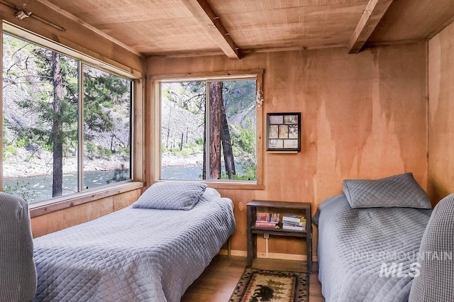 bedroom with hardwood / wood-style flooring, multiple windows, and wood walls