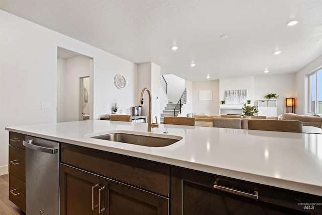 kitchen with stainless steel dishwasher, dark brown cabinets, hardwood / wood-style flooring, and sink