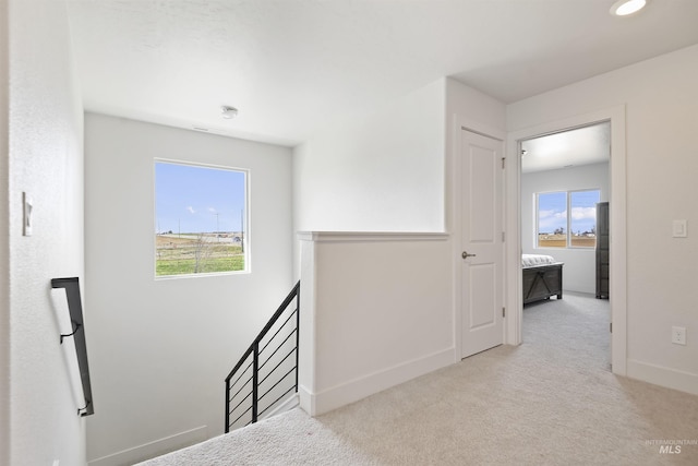 corridor featuring light colored carpet and plenty of natural light