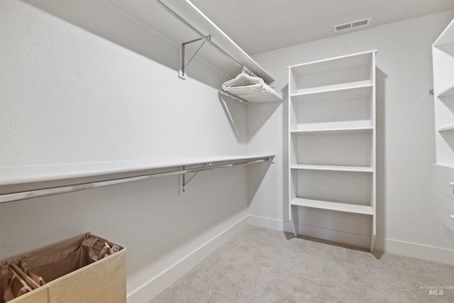 walk in closet featuring light colored carpet