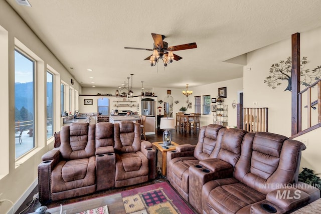 living room featuring hardwood / wood-style floors, ceiling fan with notable chandelier, and a textured ceiling