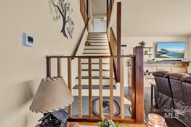 stairs featuring wood-type flooring and a textured ceiling