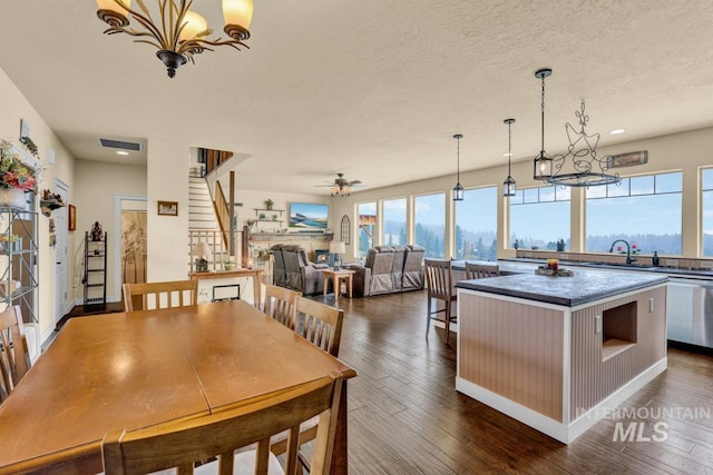 dining room featuring ceiling fan with notable chandelier, dark hardwood / wood-style floors, sink, and a textured ceiling