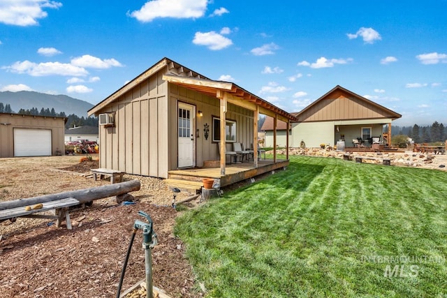 back of house with a garage, a mountain view, and a yard