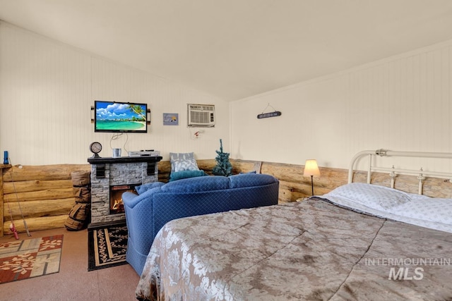 carpeted bedroom featuring lofted ceiling, a wall mounted air conditioner, and a stone fireplace