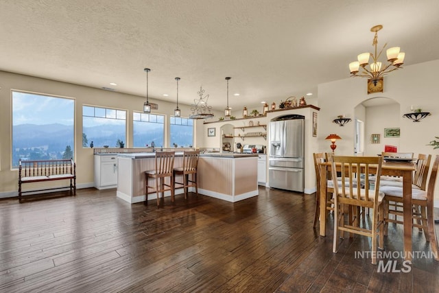 dining room with a mountain view, a chandelier, a textured ceiling, and dark hardwood / wood-style flooring