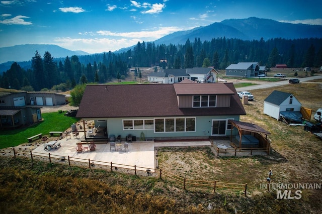 back of property with a mountain view and a patio area