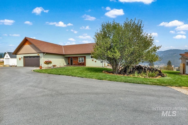 single story home featuring a garage, a mountain view, and a front lawn