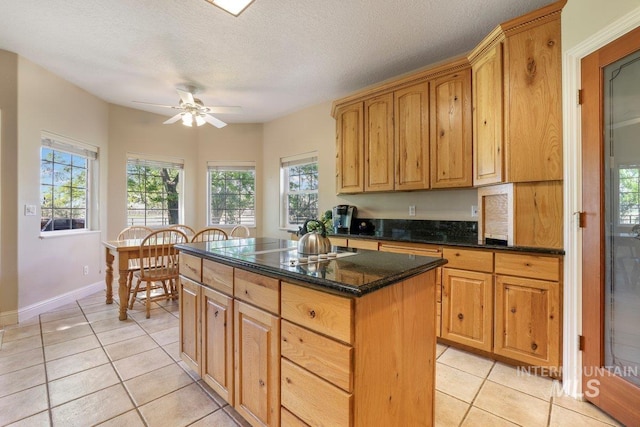 3283 Willow Cir, Twin Falls, ID 83301 - kitchen featuring light tile patterned floors, a kitchen island, a ceiling fan, dark stone countertops, and a textured ceiling