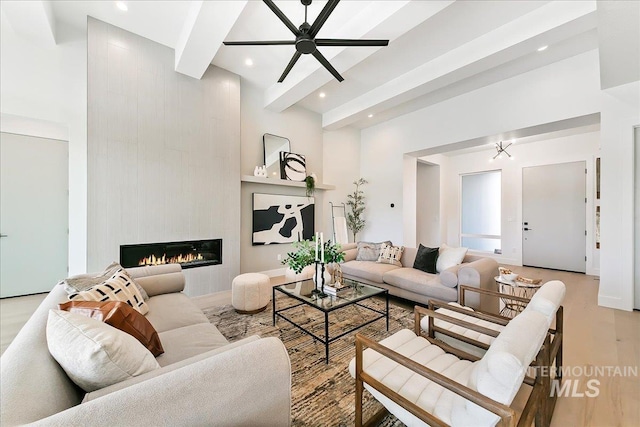 living room with a fireplace, light hardwood / wood-style floors, ceiling fan, and beamed ceiling