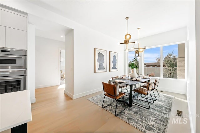 dining area with a chandelier and light wood-type flooring