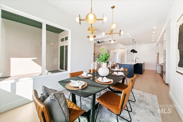 dining space with light hardwood / wood-style floors, ceiling fan, and sink