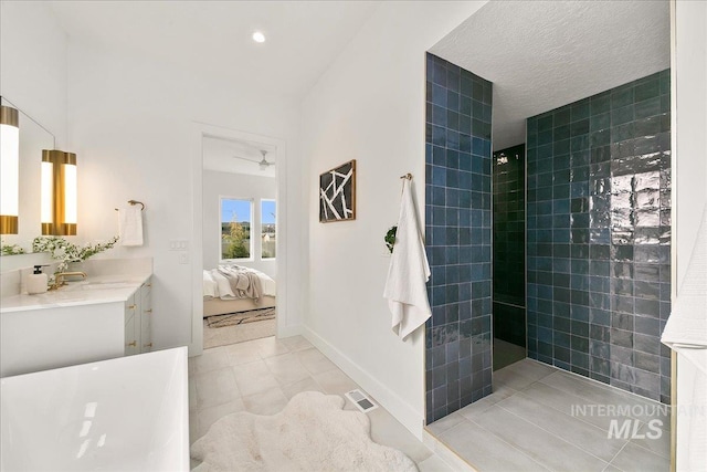 bathroom with a tile shower, vanity, tile patterned floors, and ceiling fan