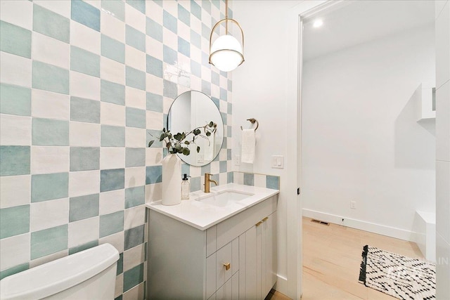 bathroom featuring vanity, toilet, and tile walls