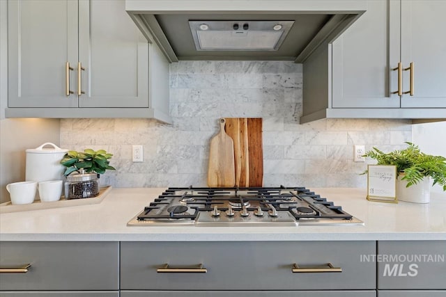 kitchen with backsplash, stainless steel gas stovetop, and gray cabinetry