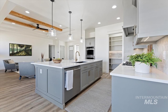 kitchen featuring ceiling fan, stainless steel appliances, tasteful backsplash, a kitchen island with sink, and hanging light fixtures