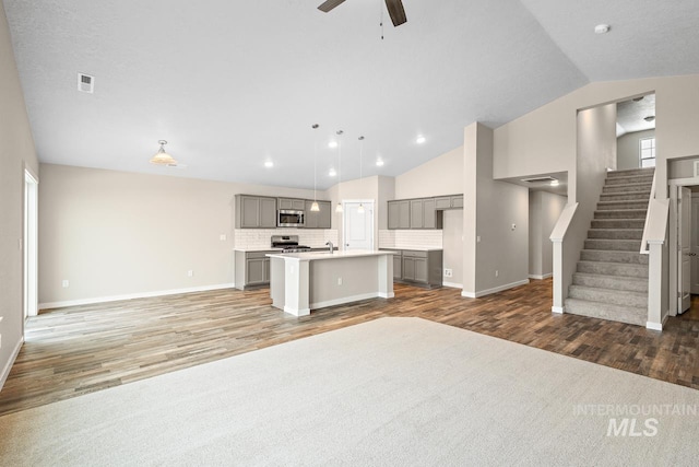 unfurnished living room featuring hardwood / wood-style flooring, ceiling fan, a healthy amount of sunlight, and vaulted ceiling