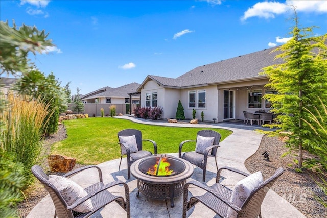 rear view of house with a patio, a lawn, and a fire pit