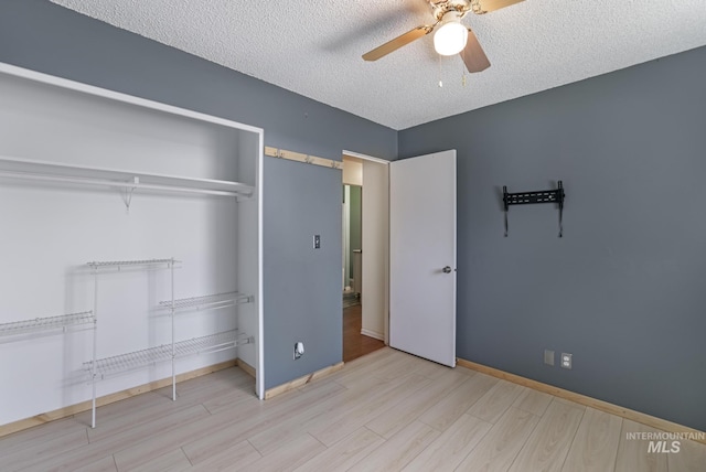 unfurnished bedroom featuring a closet, a textured ceiling, baseboards, and wood finished floors