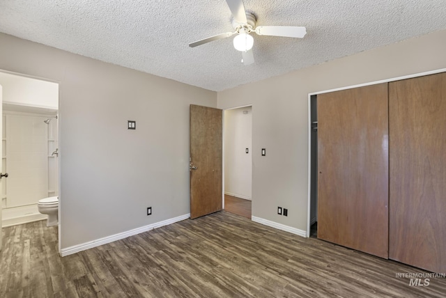 unfurnished bedroom with connected bathroom, a textured ceiling, a closet, dark wood-style flooring, and baseboards