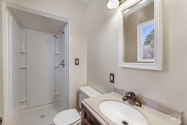 bathroom featuring toilet, a shower, and vanity