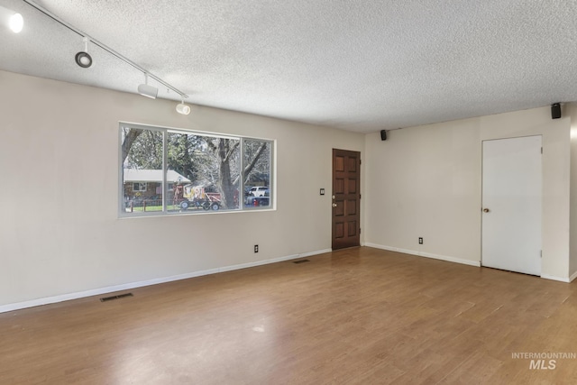 empty room with visible vents, baseboards, wood finished floors, and a textured ceiling