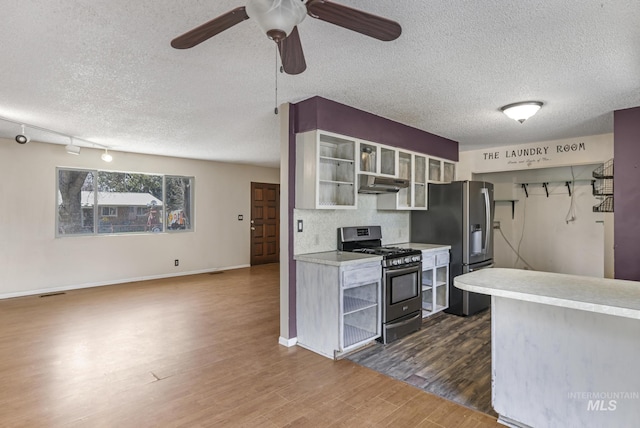 kitchen with open shelves, dark wood-style flooring, appliances with stainless steel finishes, a textured ceiling, and under cabinet range hood